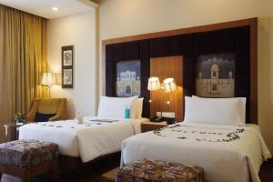 Le Meridien Jaipur Resort & Spa في جايبور: غرفة فندقية بسريرين وكرسي