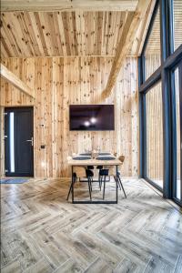 Norway Cabins في سينيا: غرفة طعام مع طاولة وتلفزيون على جدار خشبي