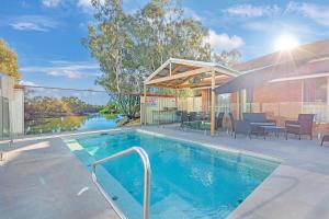 a swimming pool in front of a house at Golden River Motor Inn in Moama