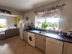 a kitchen with a washer and a sink and a microwave at Causeway Coast Country Cottage, Pet-friendly in Ballycastle