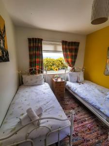two beds in a room with a window at Causeway Coast Country Cottage, Pet-friendly in Ballycastle