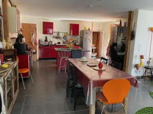 a kitchen with red cabinets and a table and chairs at CHAMBRE D HOTES CHEZ DANY MAOWMAOW ET GARFIELD in Bellevue-la-Montagne