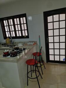 a kitchen with two stools and a counter with a stove at Casa Piratininga Niterói Rj in Niterói