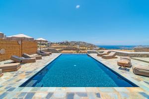 einen Pool mit Chaiselongues neben einem Resort in der Unterkunft Le Ciel Suites & Villas in Mykonos Stadt
