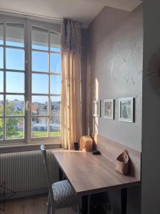 Habitación con mesa de madera y ventana grande. en Appt lumineux - 2 chambres - Mer et commerces en Berck-sur-Mer