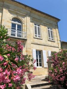 ein altes Steinhaus mit rosa Blumen davor in der Unterkunft Clos de Bertinat in Saint-Sulpice-de-Faleyrens