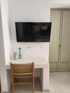 a white table with a television on a wall at ANEMOLETHE in Kimolos