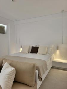 um quarto branco com uma cama grande e um sofá em ANEMOLETHE em Kimolos