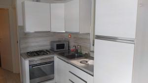a kitchen with white cabinets and a stove and a microwave at Quadrifoglio 43 in Bibione +6 photos