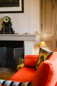 sala de estar con sofá rojo y reloj en Le Manoir De St Martin - 4 Ch - Deauville en Saint-Martin-aux-Chartrains