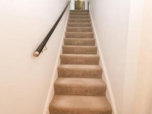 a stairway with brown carpet and white walls at Llandudno 3 Bedroom Holiday Apartment in Town Centre in Llandudno