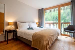 um quarto com uma cama e uma grande janela em Montela Hotel & Resort - Suiten em Saas-Grund