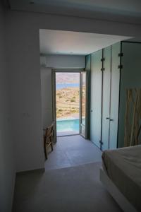 een slaapkamer met een deur naar een zwembad bij ANEMOLETHE in Kimolos