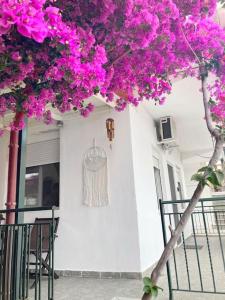 a tree with pink flowers on the side of a house at Mokamvilia House in Ammouliani