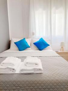 a bed with blue pillows and white towels on it at Mokamvilia House in Ammouliani
