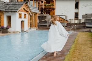 una donna con un vestito bianco in piedi accanto alla piscina di Natur- und Wellnesshotel Höflehner a Haus im Ennstal