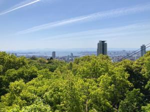 einen Blick auf die Stadt von den Baumkronen in der Unterkunft Guesthouse KOBE YAMATOMUSUBI in Kōbe