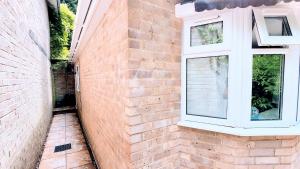 eine Backsteinmauer mit einem Fenster an der Seite eines Gebäudes in der Unterkunft 1 Bedroom Annex - Close to Frimley Hospital - Private Entrance in Frimley
