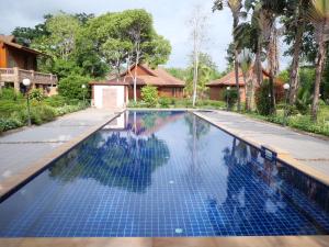a swimming pool with blue tiles in front of a house at Sasidara Resort Nan in Nan