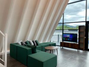 a living room with a green couch and a tv at Qafqaz Falcon Chalet in Gabala