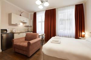 a hotel room with a bed and a chair and a kitchen at Stabu Sēta Apartments in Riga