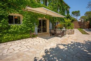 un patio con un banco y una sombrilla en Villa provençale proche de la mer, en Boulouris-sur-Mer