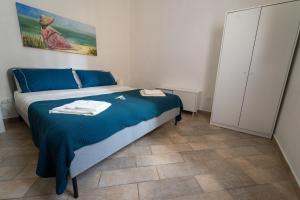 een slaapkamer met een bed met blauwe lakens en een kast bij Le Casette di Didi in Trapani
