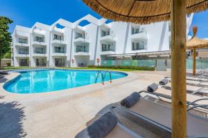 einen Pool vor einem Hotel mit Stühlen und einem Sonnenschirm in der Unterkunft Apartamentos Bellamar in Port de Pollença
