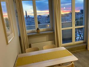 een tafel en stoelen in een kamer met ramen bij Apartament Zachody nad Wrocławiem in Wrocław