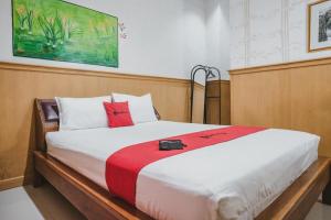 1 dormitorio con 1 cama grande con almohadas rojas y blancas en RedDoorz near Kartini Mall Lampung en Bandar Lampung