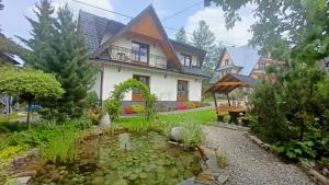 a house with a pond in front of it at Domek z Góralską Duszą Śleboda in Jurgów