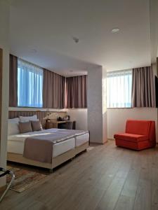 1 dormitorio con 1 cama grande y 1 silla roja en Hotel Emerald, en Mostar