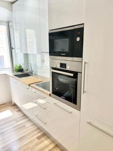 een witte keuken met een fornuis en een magnetron bij Luxury apartment Aura in Supetar