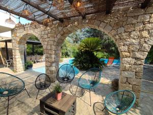 an outdoor patio with chairs and a stone wall at Villa A CASA DI FICU proche d'Ajaccio avec piscine et jacuzzi in Peri