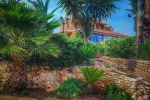 einen Garten mit Palmen und einer Steinmauer in der Unterkunft Villa Vella in Syrakus