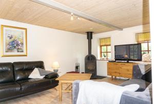 ein Wohnzimmer mit einem schwarzen Ledersofa und einem Holzofen in der Unterkunft Krog Feriehus in Billund