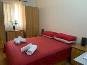 a bedroom with two towels on a red bed at Caris Gem in Birżebbuġa