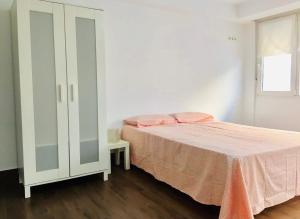 a white bedroom with a bed and a cabinet at Apartamento familiar Torrelavega in Torrelavega