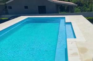 a swimming pool with blue water in front of a house at Villa Eglantine in Grand Gaube