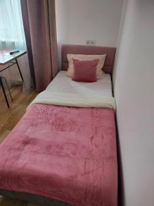 a small bed with a pink blanket on top of it at Hostel 11 in Kozienice