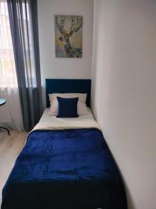 a bedroom with a bed with a blue blanket at Hostel 11 in Kozienice