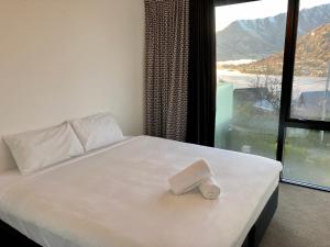 a bed with a book on it in front of a window at Highview terrance 3 bedrooms house queenstown in Queenstown
