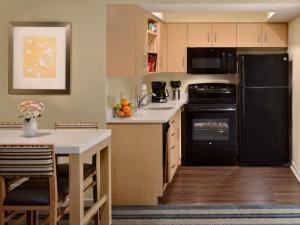 uma cozinha com um frigorífico preto e uma mesa em Sonesta ES Suites St. Louis Westport em Maryland Heights