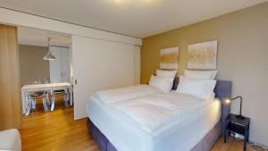サンモリッツにあるLac 15のテーブル付きの客室で、白い大型ベッド1台が備わります。