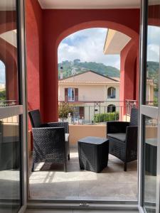 a balcony with chairs and a table and a building at Aether Suites Tropea - Free Parking in Tropea