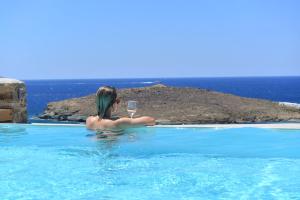 una mujer sosteniendo una copa de vino en una piscina en Horizon Villas, en Agios Ioannis