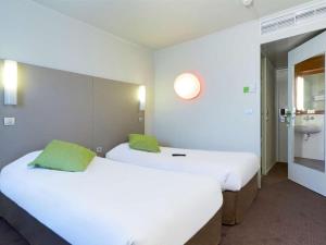 two twin beds in a room with a bathroom at Campanile Cergy-Pontoise in Pontoise