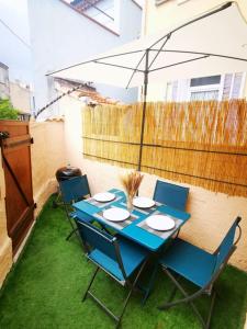 濱海聖芒德里耶的住宿－Jolie Maison au coeur du village，一张带椅子的蓝色桌子和一把雨伞