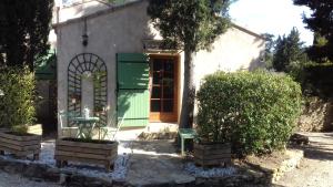 una pequeña casa con una puerta verde y una ventana en Chambre d'hote, en Le Beausset