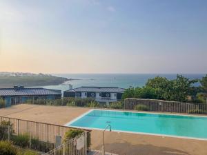 a swimming pool with the ocean in the background at Lagrange Vacances - Les Terrasses de l'Océan in Audierne